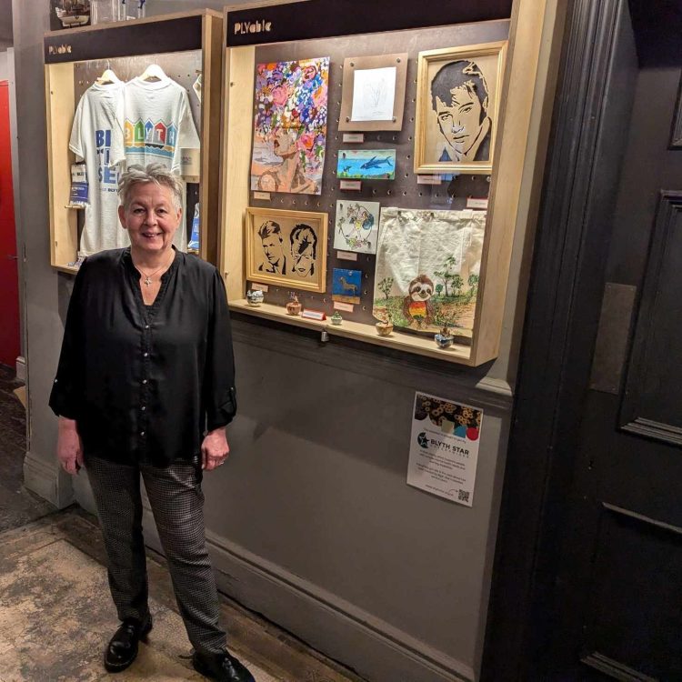 A woman stands in front of an art gallery exhibit